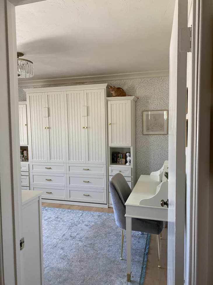A bedroom with a large white wardrobe and a white desk