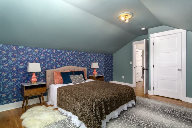A bedroom with blue walls and a blue wallpaper accent wall