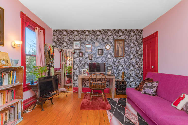 A pink office with a floral accent wall and a magenta couch