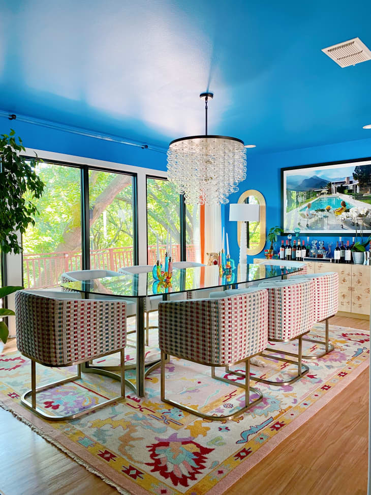 A blue dining room with a glass table and chairs