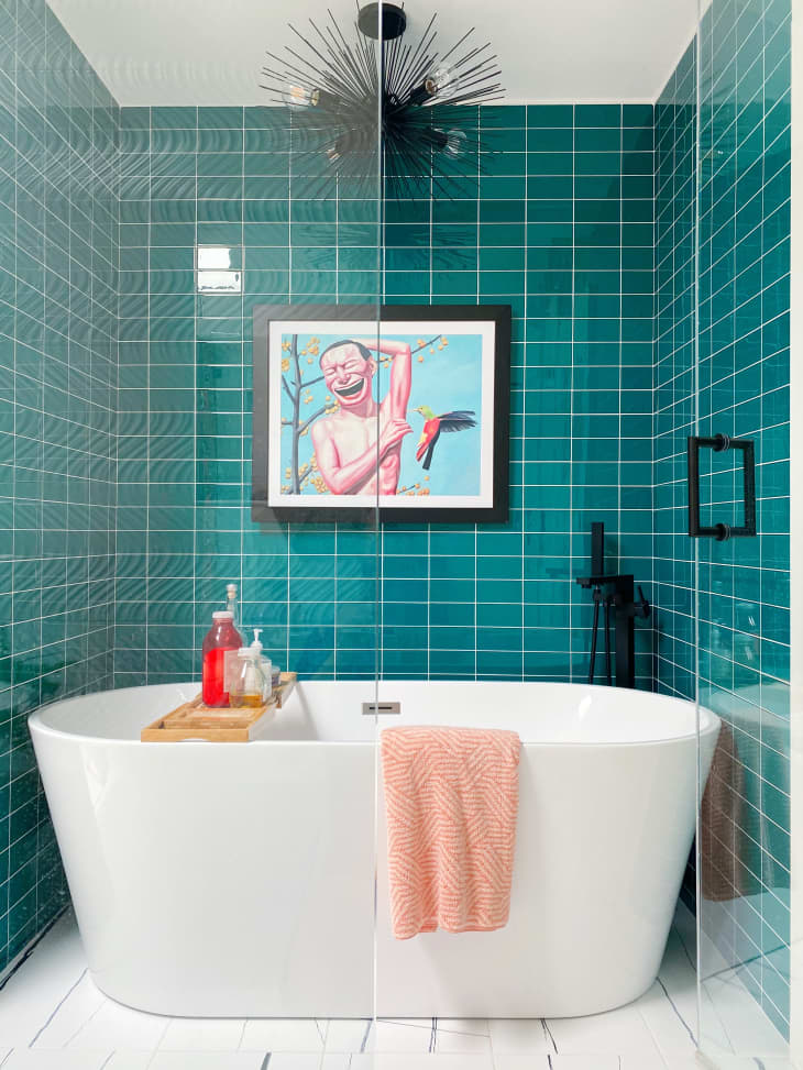 A bathroom with blue-green tiles around the tub