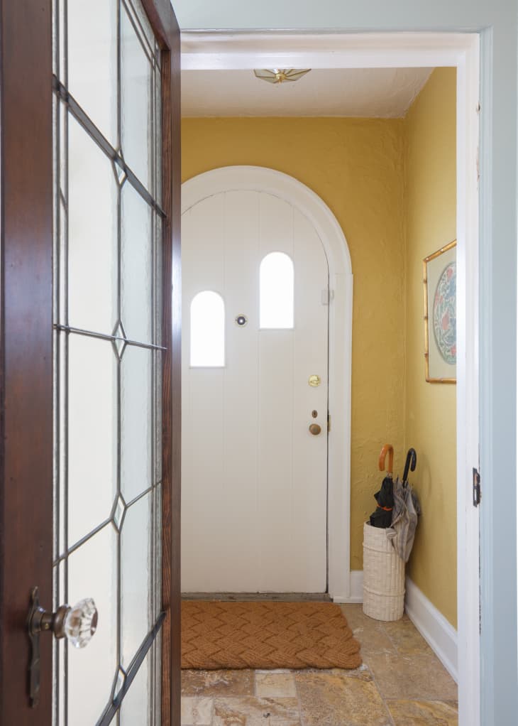Rounded door in yellow entryway of home.