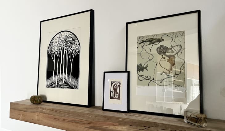 wood floating shelf with framed drawings/paintings
