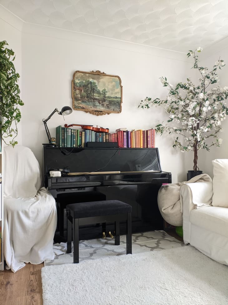 Piano with books on top in light filled living room.