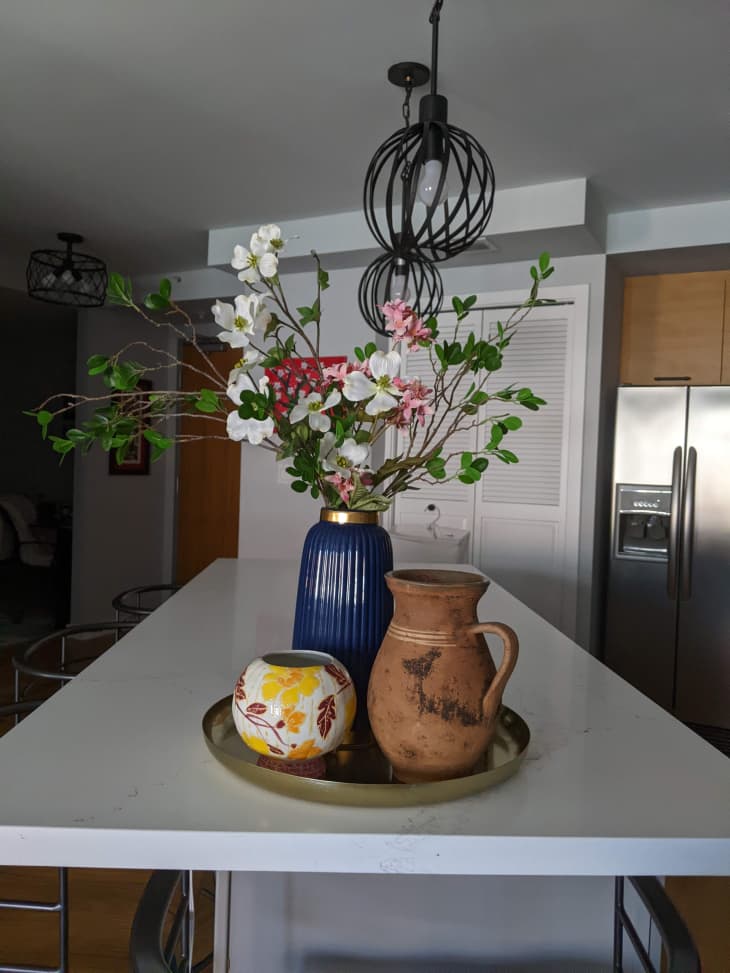 Still life on the kitchen counter with vase of flowers and various jugs and ceramics around.