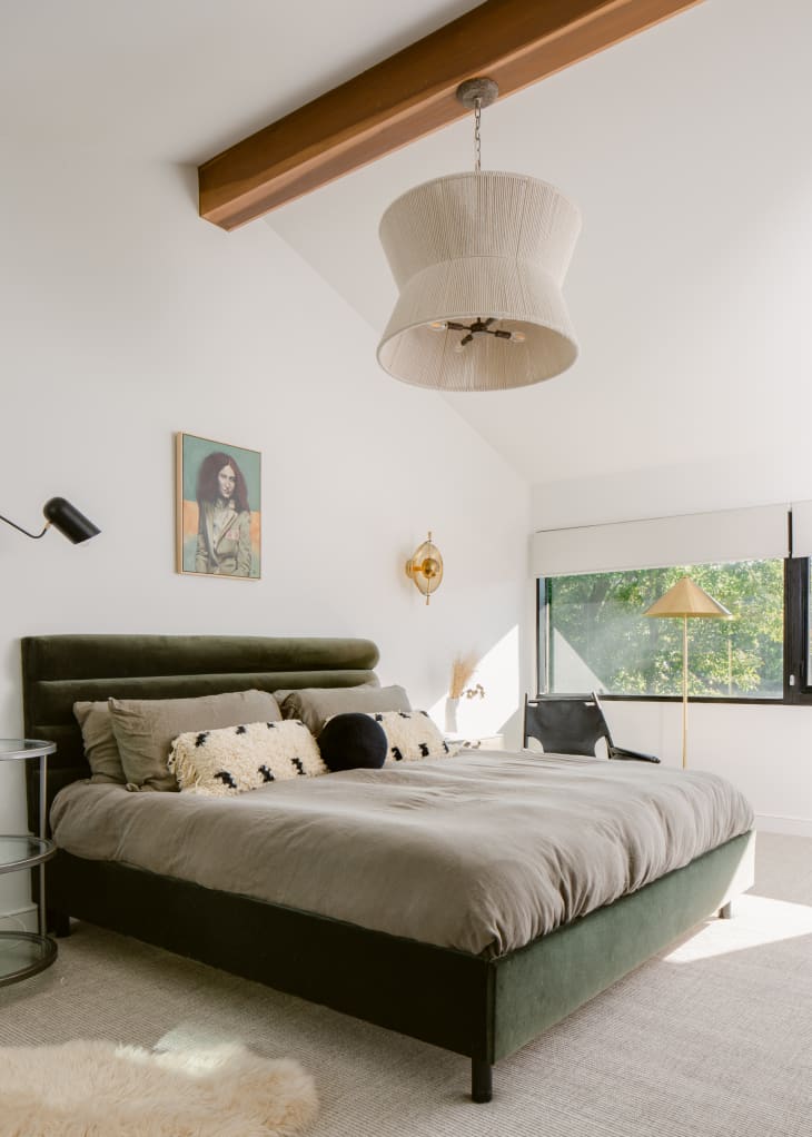 Contemporary bedroom with lofted ceiling with wood rafter, large cloth hanging pendant light, and green velvet tufted bedframe.