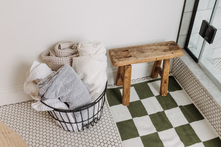 Philadelphia residence with white walls, lots of wood details: wire basket with towels and small wood bench next to shower in bathroom