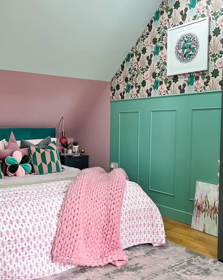 bedroom with pink. mint, white walls with pink and green botanical wallpaper, bed with pink, white and green bedding, angled ceiling