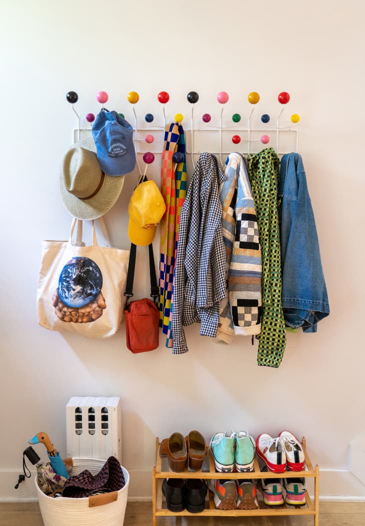 Colorful hook rack in entryway with lots of bags, hats and jackets.