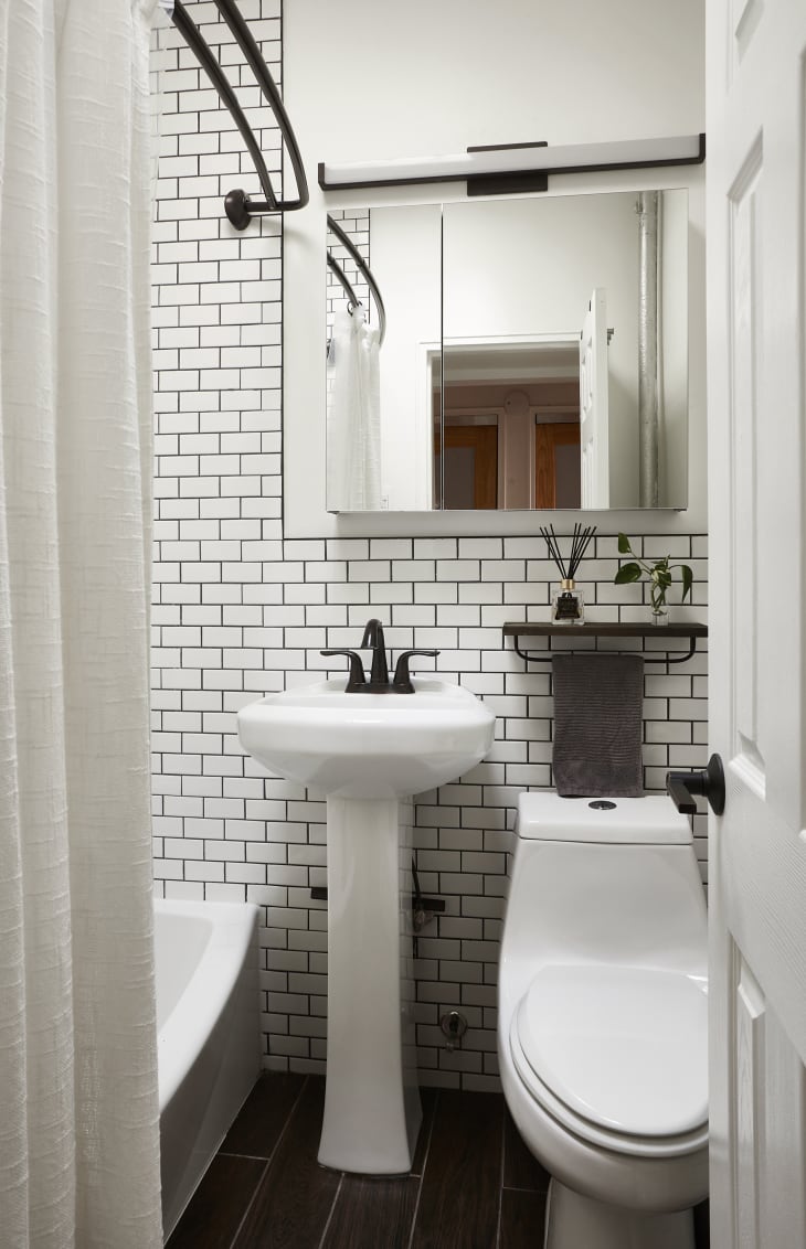 bathroom with white tile and black grout walls, white sink with black hardware