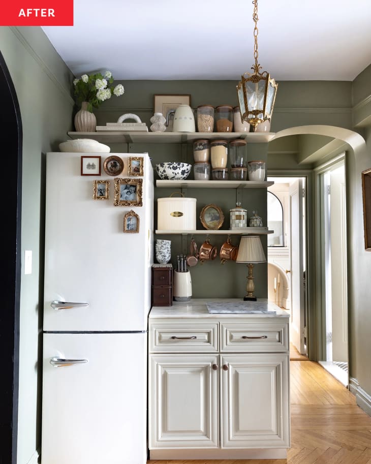 Olive green kitchen with custom shelving and antique pendant after renovation.