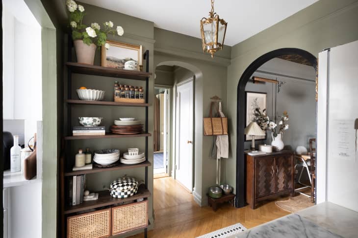 Arched entry ways in neutral kitchen with gray-green walls, wood floors and open shelving