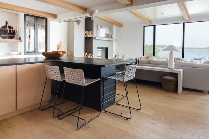 kitchen/dining area with white walls, ceiling, wood accents and beams, black counter with white stools