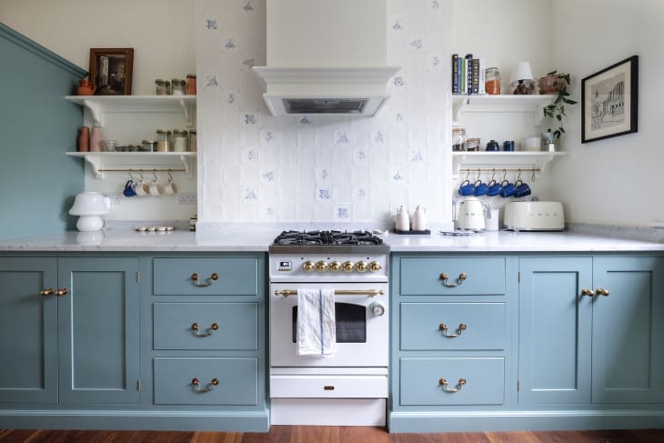 Blue cabinets in kitchen with blue and white backsplash tiles.