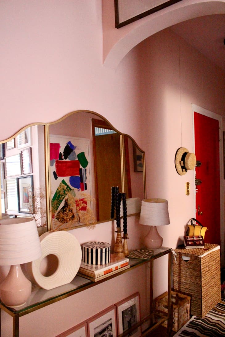 Mirror mounted over table in pink painted entryway.