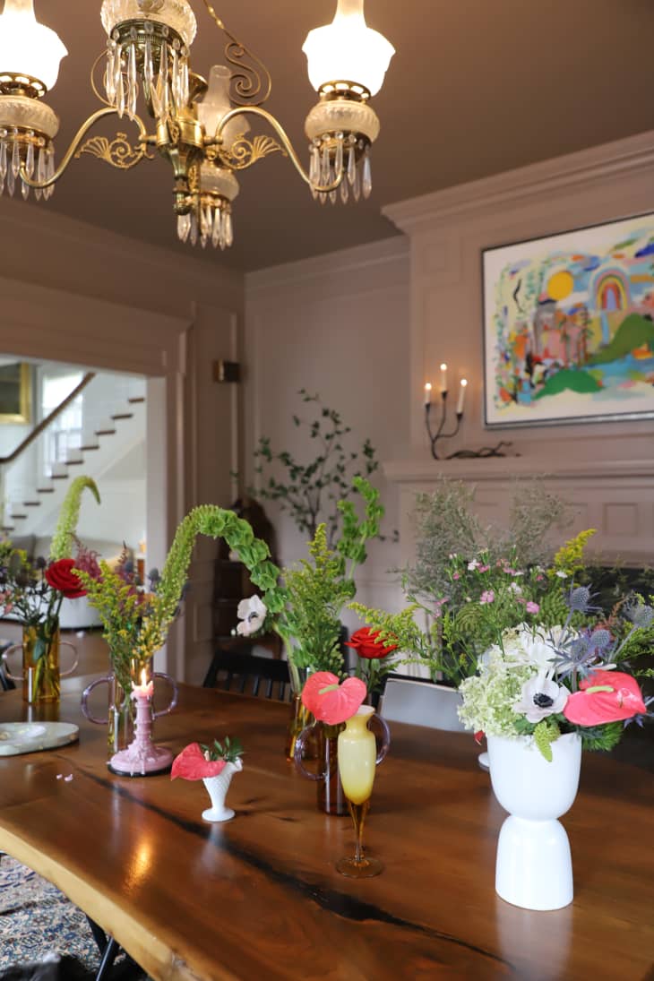 Floral arrangements line dining room table in Farrow and Balls Dead Salmon painted living room.