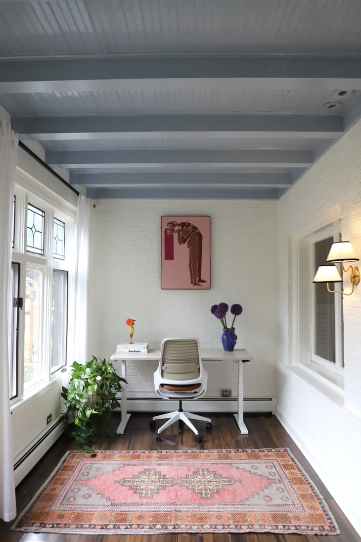 Pink and brown painting above writing desk in white painted home office with pink rug lining the floor.