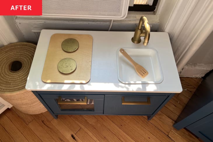 kids play kitchen set painted blue with white counter and 2 wood burners, small sink and storage underneath