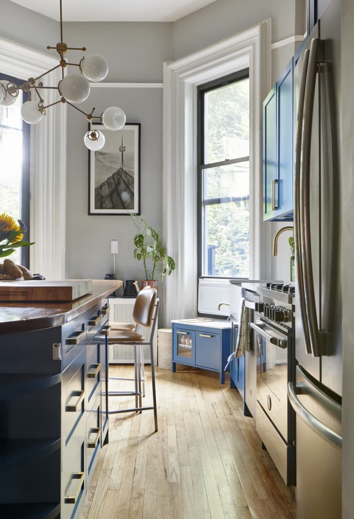 Blue cabinets in gray-painted kitchen with multi-armed pendant lamp hanging over island.