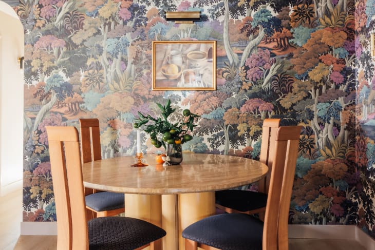 dining room with trees wallpaper and wood round dining table