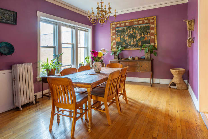 Purple dining room with large rustic wood dining table and chairs, and boho elements