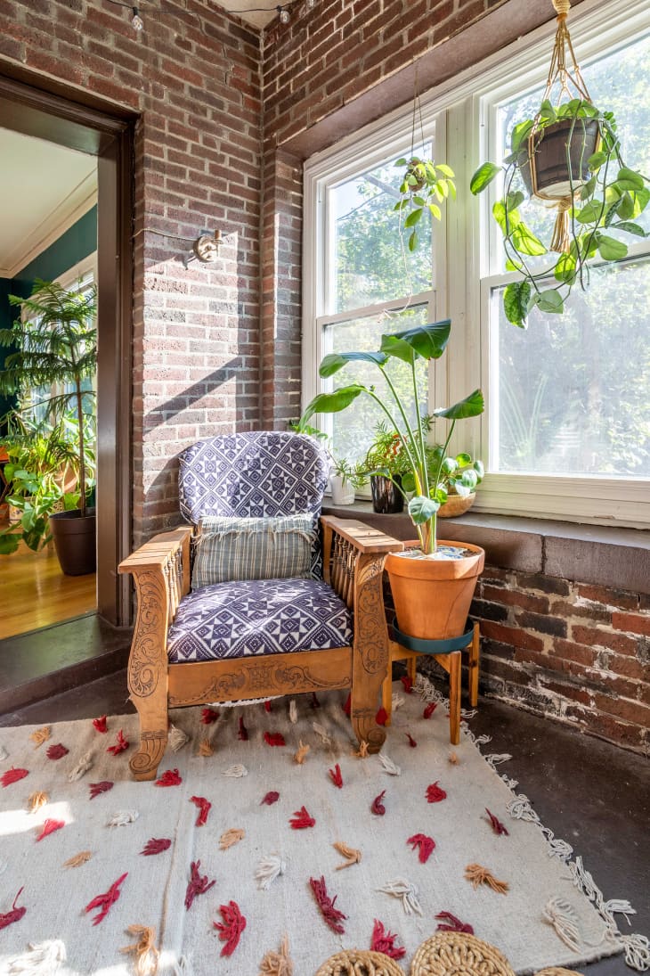 Exposed brick sunroom with plants and boho armchair