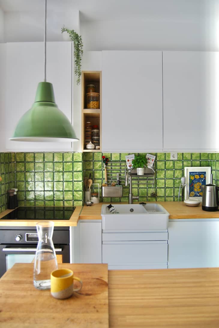 Kitchen view with green backsplash and white cabinets.