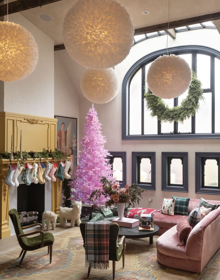 Stockings hang on a yellow fireplace in a living room with a large pink tree.