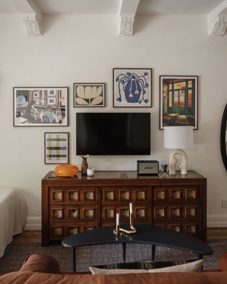 Art prints surround media console in newly remodeled apartment.