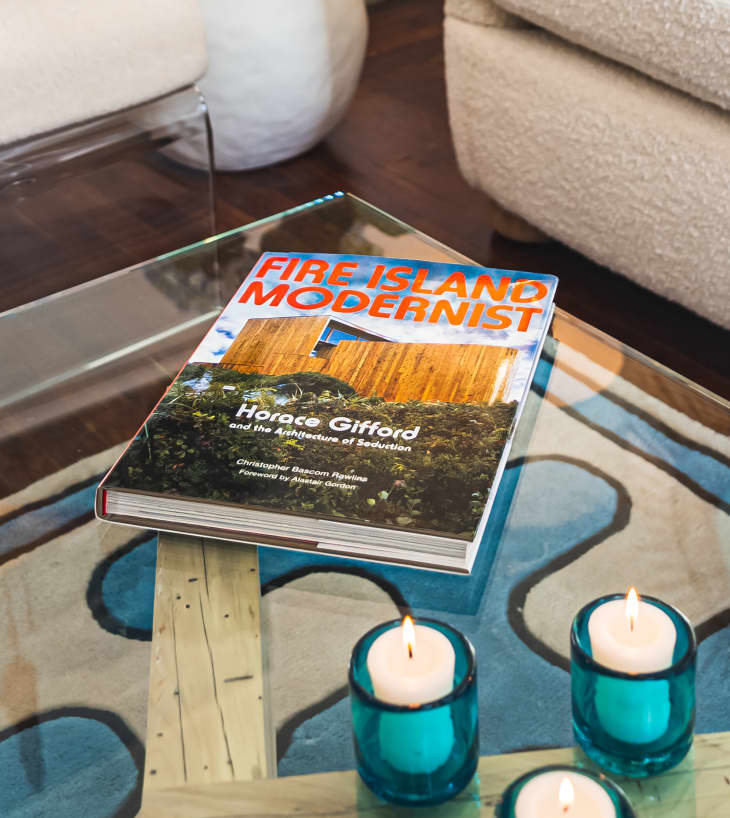 glass coffee table with book, "Fire Island Modernist" and some votive candles