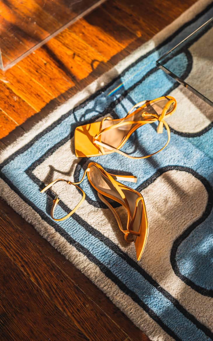 A pair of yellow heeled sandals on a rug