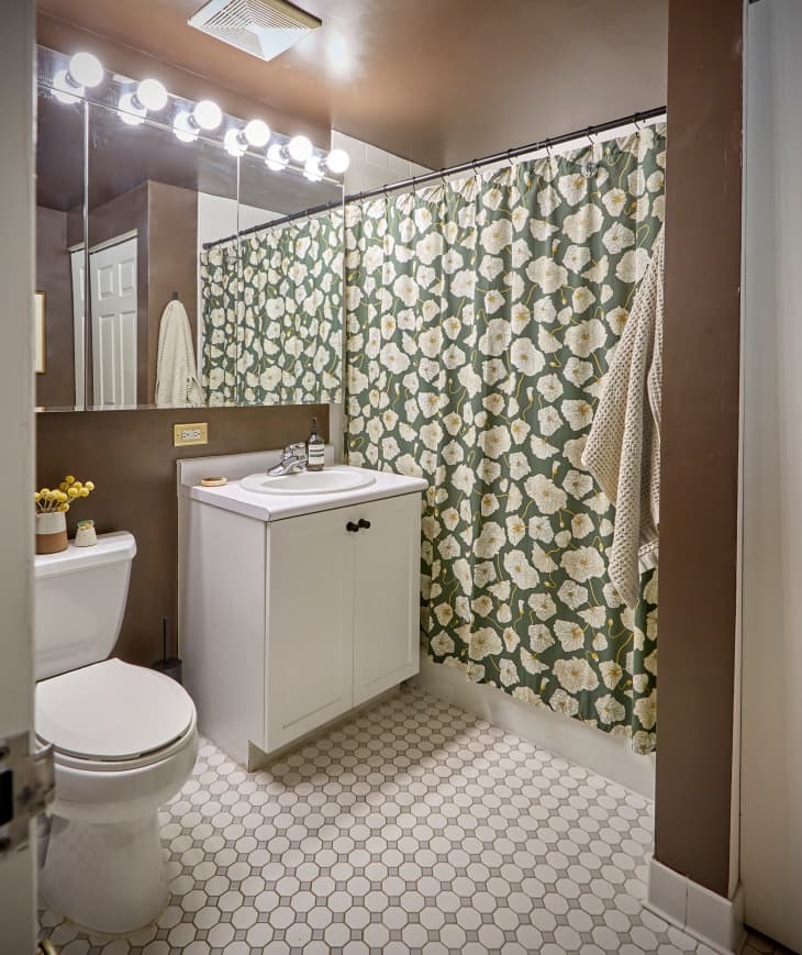 bathroom with floral shower curtain, circle tile floor, white cabinet/sink