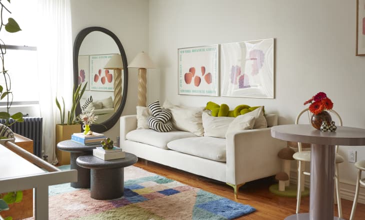 A white couch in a white living room with colorful artwork and a colorful rug