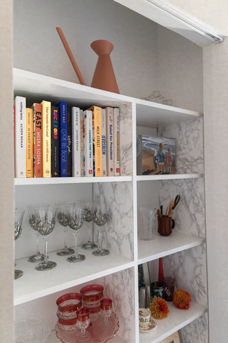 A shelving unit holding books and glasses