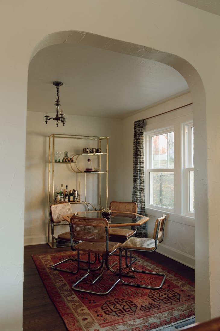 An archway to a dining room with a round glass table and four chairs