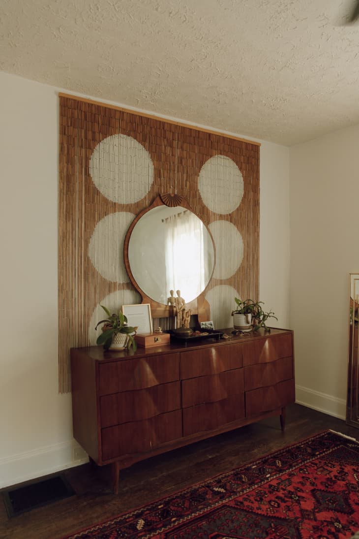 A credenza with a large round mirror above