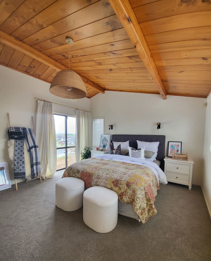 A bedroom with wooden ceiling panels and white walls