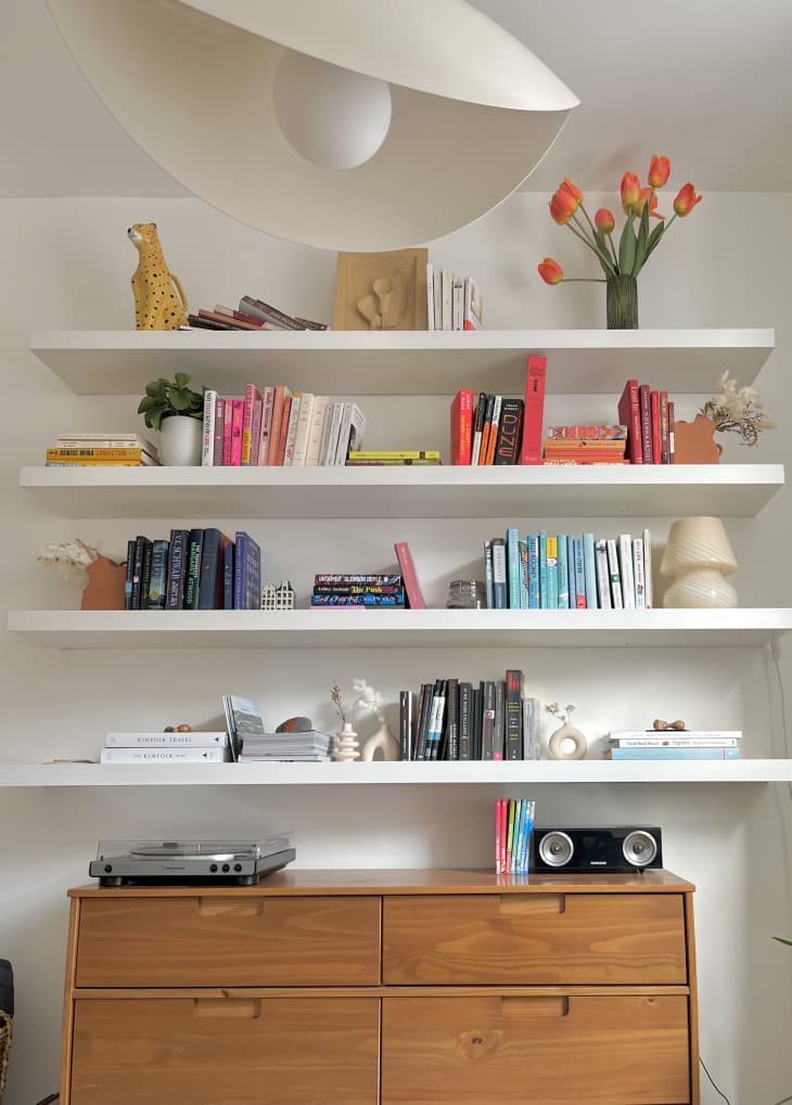 Four white bookshelves over a brown dresser