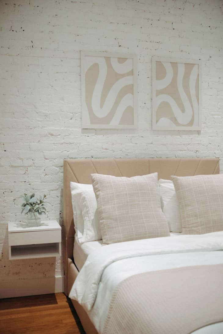 A white brick bedroom with white floating nightstands