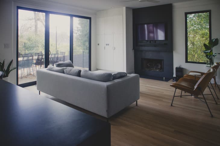 A living room with a gray sofa and two chairs looking out to a patio