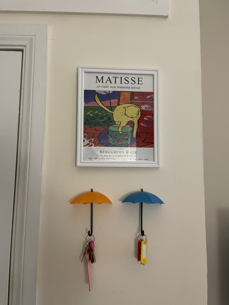 A Matisse print of a cat above two umbrella shaped key holders