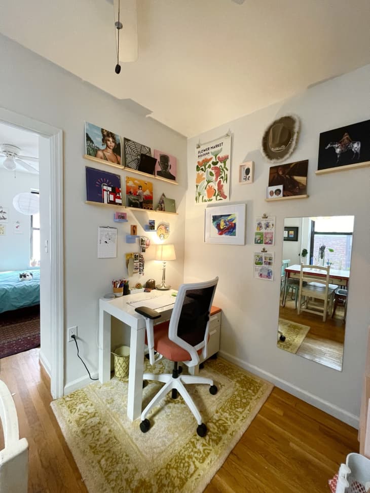 Office space with small white desk and albums displayed on walls.