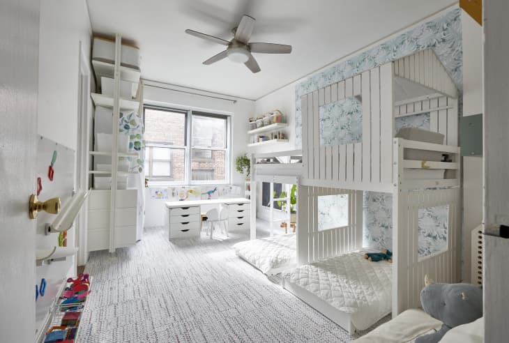 Light colored kids room with treehouse like bunkbed and desk near window.