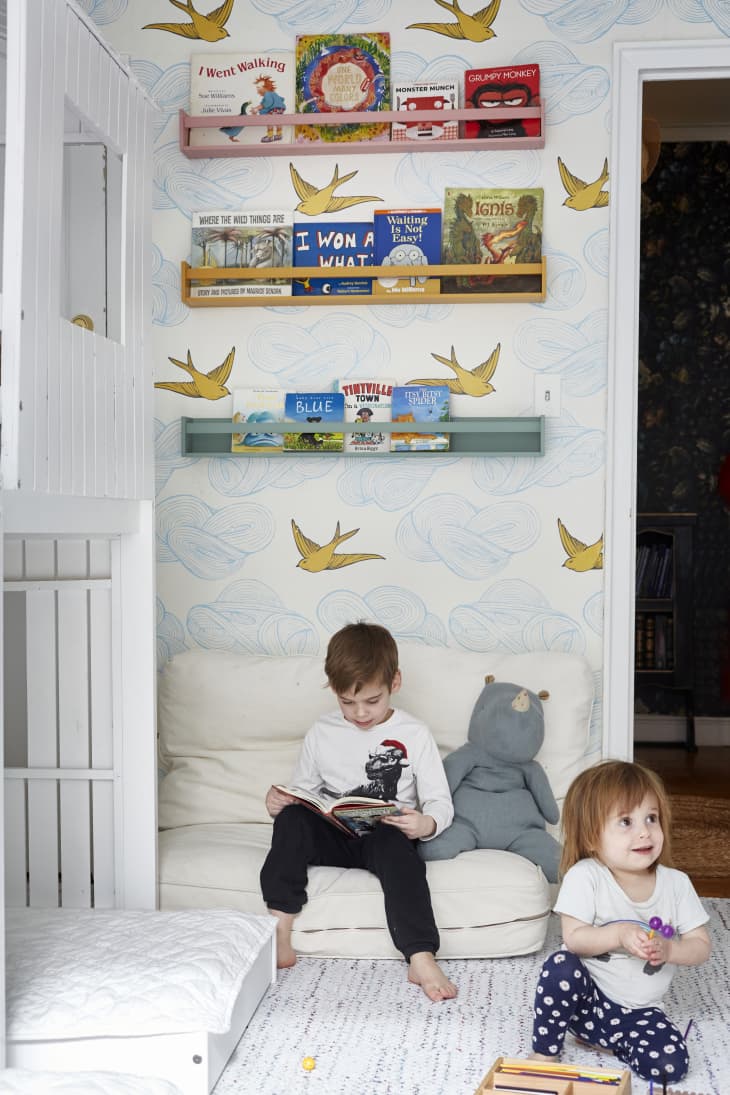 Two small children playing and reading in a nook.
