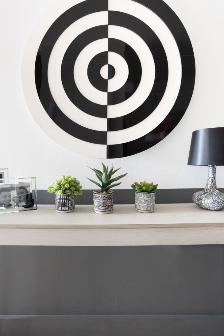 Detail of black and white graphic circle/target art. Plants and lamp on accent table underneath