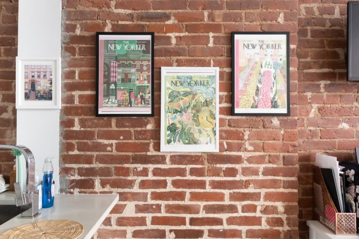 The New Yorker Magazine cover art hanging on brick wall of apartment.