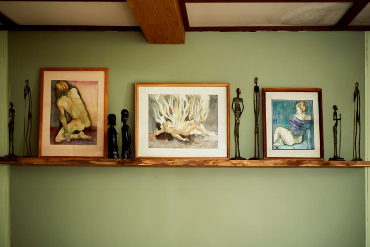 framed art and sculptures on the floating wood mantle. pale green walls