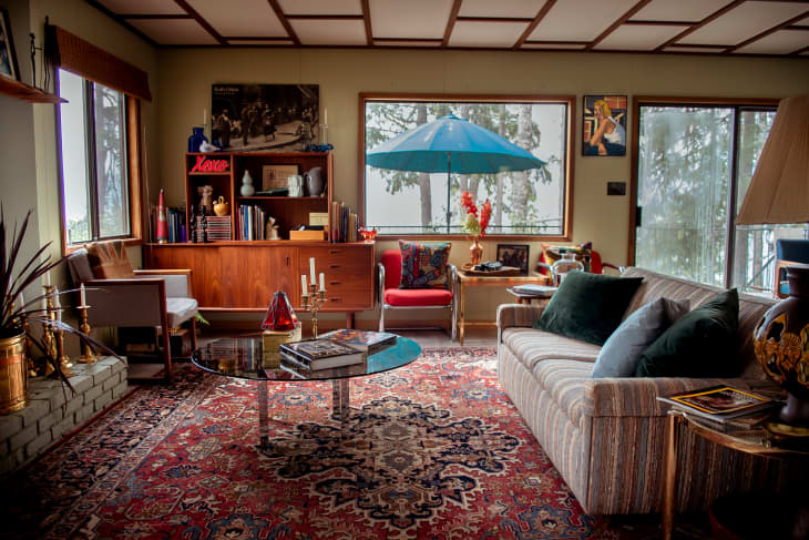 Living room with persian style rug, striped sofa, round mirror coffee table, vintage wood furniture