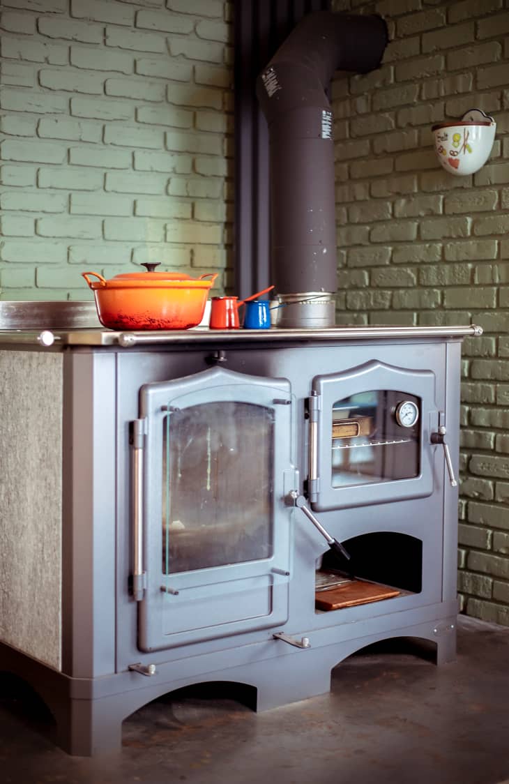 wood burning stove in front of pale green painted brick wall