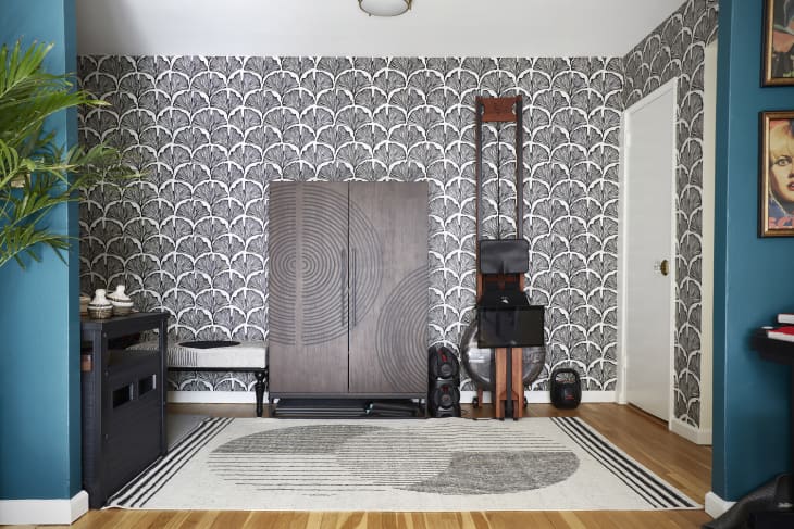 Room with black and white patterned wallpaper, workout machine, storage cabinet